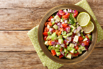 Delicious summer salad of tomatoes, onions and avocado close-up in a plate on the table. horizontal top view from above