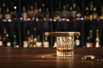 close up view of cigar and glass of whiskey on color back. 