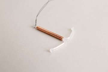 Copper intrauterine contraceptive device on light background