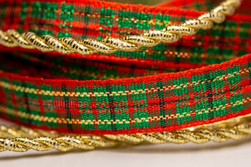 Macro abstract texture background of red and green Christmas plaid ribbon and gold color twisted rope ribbon with copy space