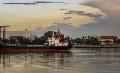 Fototapeta premium Bangkok, Thailand - Jul 31, 2021 : View of Chao phraya river has cargo ships docked in the middle river and the back is Wat Bangkrachaonok area. No focus, specifically.