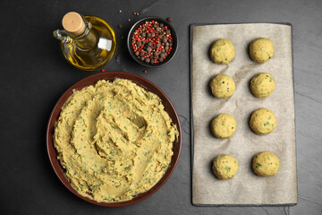 Raw falafel balls and ingredients on black table, flat lay