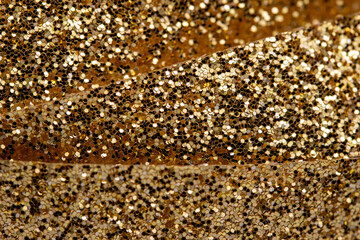 Macro abstract texture background of sparkling gold color Christmas holiday glitter ribbon with bokeh and copy space
