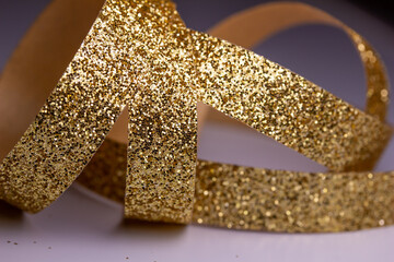 Macro abstract texture background of sparkling gold color Christmas holiday glitter ribbon with bokeh and copy space
