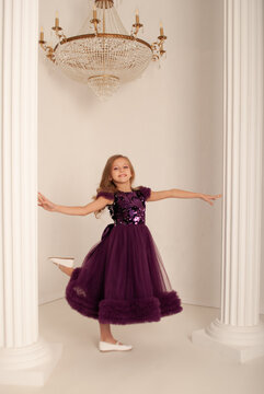 girl 8 years old on the holiday new year and Christmas 2022 dances in a dress against the background of a huge chandelier concept minimalism
