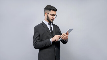 businessman standing wearing glasses using tab in black suit indian pakistani model
