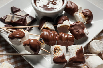 Plate of tasty grilled marshmallows with chocolate on light background