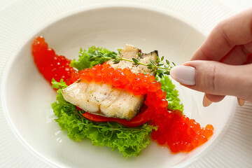 Woman decorating plate of tasty sea bass fish with thyme, closeup