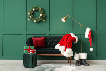 Interior of stylish room with comfortable sofa, Santa Claus costume and boots near color wall