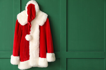 Santa Claus costume hanging on color wall