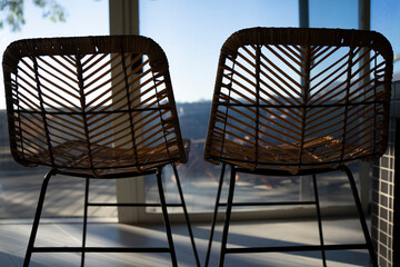 Fototapeta na wymiar Back of two wicker chairs side by side with view of sky in the background.