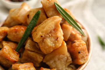 Bowl with tasty cracklings on table, closeup