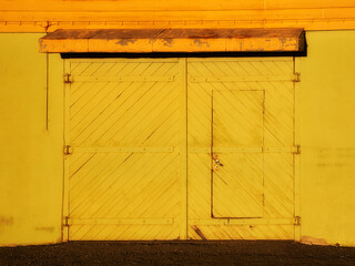 yellow wooden gate with a door in the wall