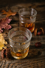 Glasses of chestnut whiskey on wooden background