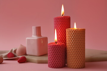 Beautiful burning candles and perfume bottle on color background