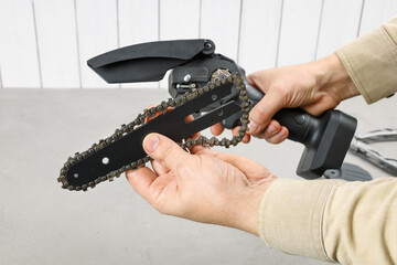Removal, installation of chain into electric portable saw with disconnected battery. From series,...