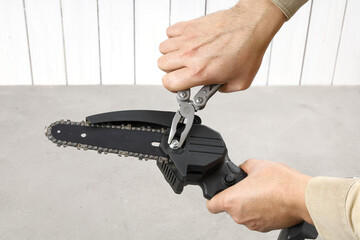 Hands fix nut on portable chain saw with multitool. From series, tool preparation for work