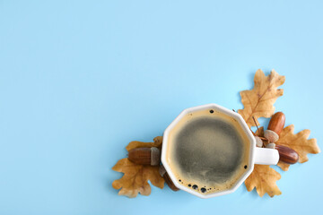 Cup of coffee with acorns and autumn leaves on blue background