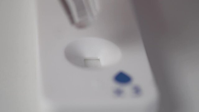Close-up, casset test for covid-19, a drop from a pipette falls into the window for analysis on the test.