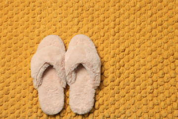 Fototapeta na wymiar Slippers on soft orange bath mat, flat lay. Space for text