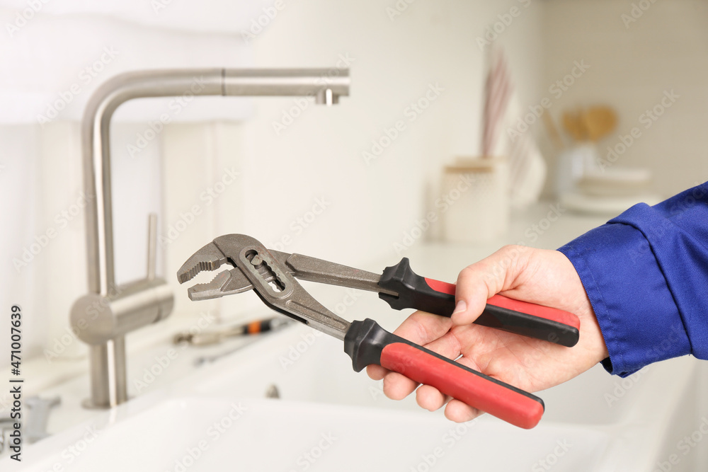 Wall mural plumber with spanner near sink in kitchen, closeup. water tap installation