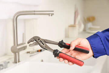 Plumber with spanner near sink in kitchen, closeup. Water tap installation