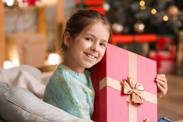Fototapeta na wymiar Cute little girl with gift at home on Christmas eve