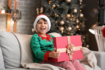 Obraz na płótnie Canvas Cute little boy with gift at home on Christmas eve