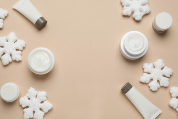 Cosmetic products and snowflakes on beige background, flat lay with space for text. Winter skin care
