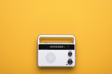 Retro radio receiver on yellow background, top view