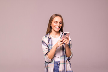 Young woman posing isolated over white wall background using mobile phone.