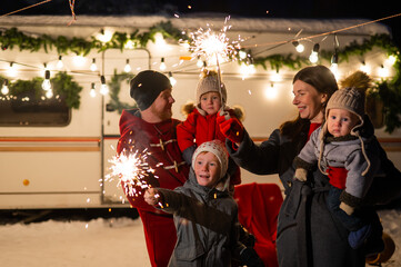 Happy family celebrates christmas in nature and holds sparklers. Parents with three sons travels in...