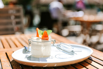 Vanilla pudding with strawberries at sunny terrace wooden table