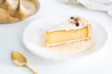 French flan on white plate with biscuit crumbs around, with almonds on top. Piece of cake on white bright background, traditional french  dessert