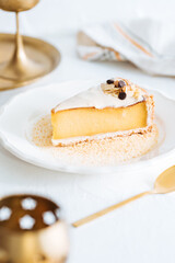 French flan on white plate with biscuit crumbs around, with almonds on top. Piece of cake on white bright background, traditional french  dessert