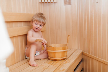 Beauty, healthcare. baby Boy relaxing in the sauna Toddler with broom and hat in russian sauna or bath