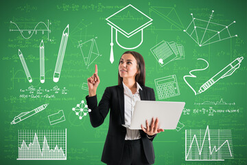 Portrait of happy young european businesswoman with laptop pointing up at creative knowledge and graduation sketch on green wall background. Education and academic concept. - Powered by Adobe