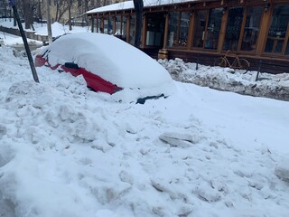 Snow covered car after heavy snowfall . Snowbound car. Traffic in winter. Car under snow on city street.