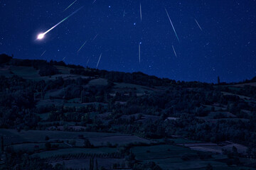 Silhouette of countryside landscape under the starry skies and meteor shower.