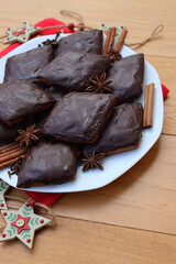 Italian traditional festive cookies called Mostaccioli or Mustaccioli on a plate on red napkin with festive decorations on wooden table. Christmas cookies made mith Pisto, a mix of various spices