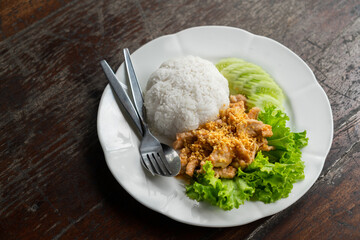 Deep-fried pork with garlic with Jasmine white rice in white plate, vegetable salad and cucumber for the side dish, Thai food easy menu, close up image.