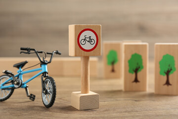 Traffic sign No cycling and toy bicycle on wooden table. Passing driving license exam