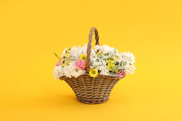 Fototapeta na wymiar Basket with beautiful flowers on yellow background