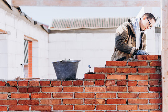man building brick wall, bricklayer