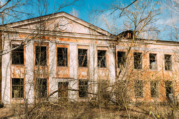Fototapeta na wymiar Abandoned Ruined Old Village School Building In Chernobyl Resettlement Zone. Belarus. Chornobyl Catastrophe Disasters. Dilapidated House In Belarusian Village. Whole Villages Must Be Disposed