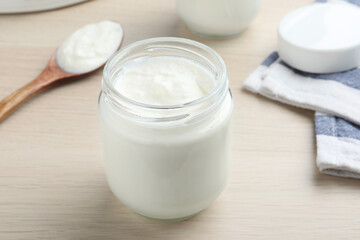 Glass jar with tasty yogurt on white wooden table, closeup