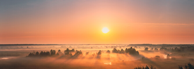 Amazing Sunrise Sunset Misty Landscape. Scenic View Of Foggy Morning Sky With Rising Sun Above Misty Forest And River. Early Summer Nature Of Eastern Europe. Panorama