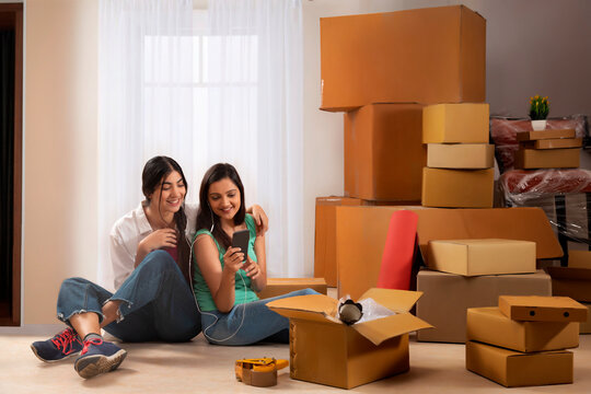 Adult girls listening music while sitting on floor during leisure time