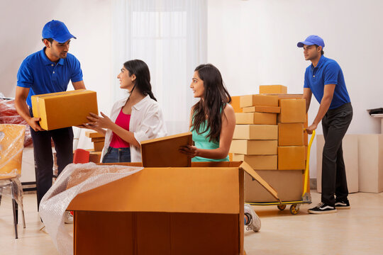 Delivery boys moving carton boxes and helping girls in packing