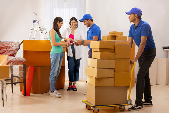 Adult girls checking list of carton boxes with delivery boys before delivery